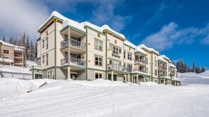 Et hotel med flere etager og altaner, beliggende på en sneklædt skråning.
