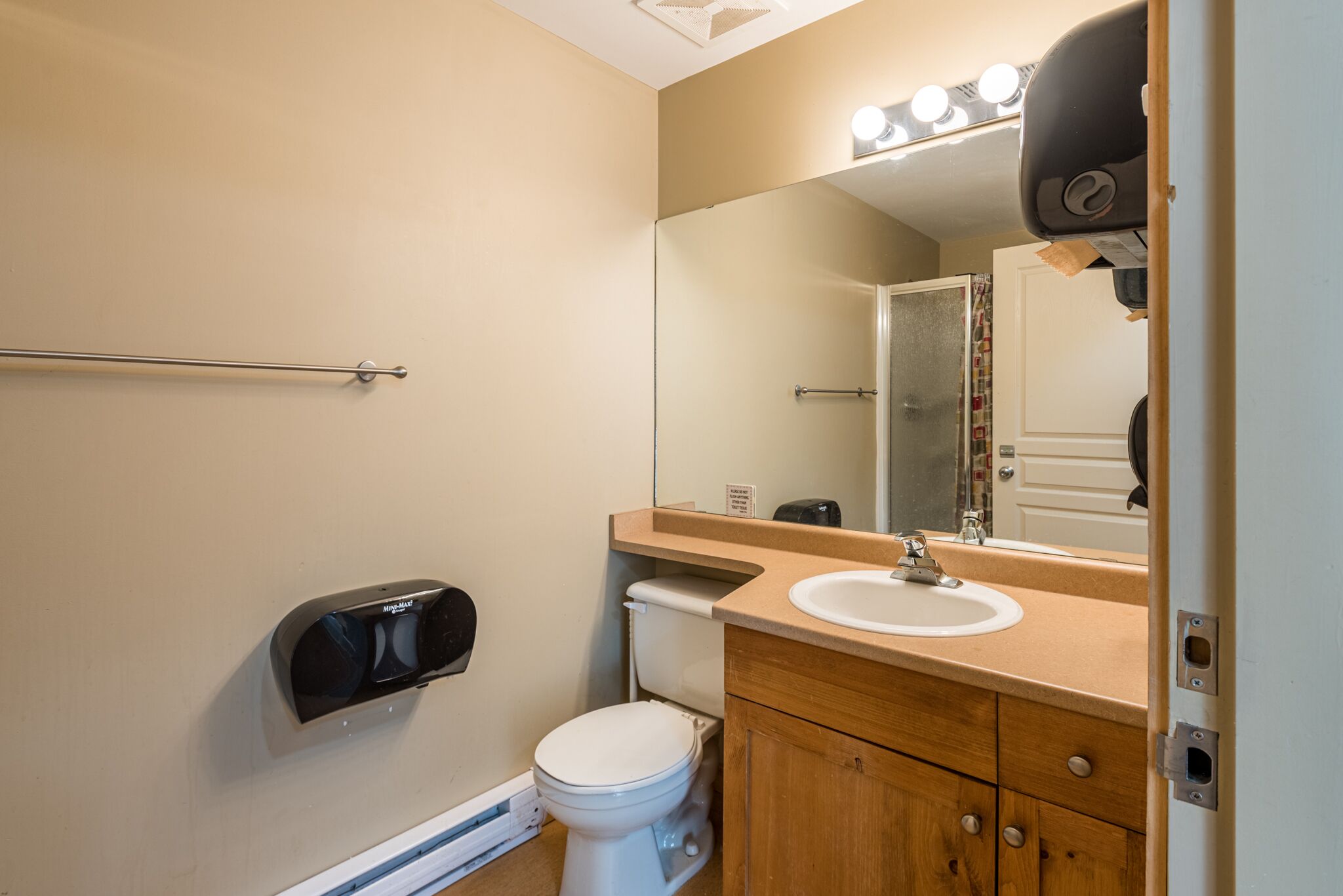 A bathroom with a toilet, sink, and mirror.