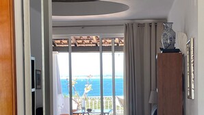A modern living room with a view of the sea, a balcony, and a dining area.