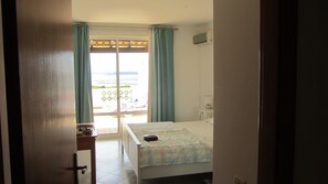 Une pièce avec un lit, une fenêtre avec des rideaux, une petite table et une vue sur l’extérieur.
