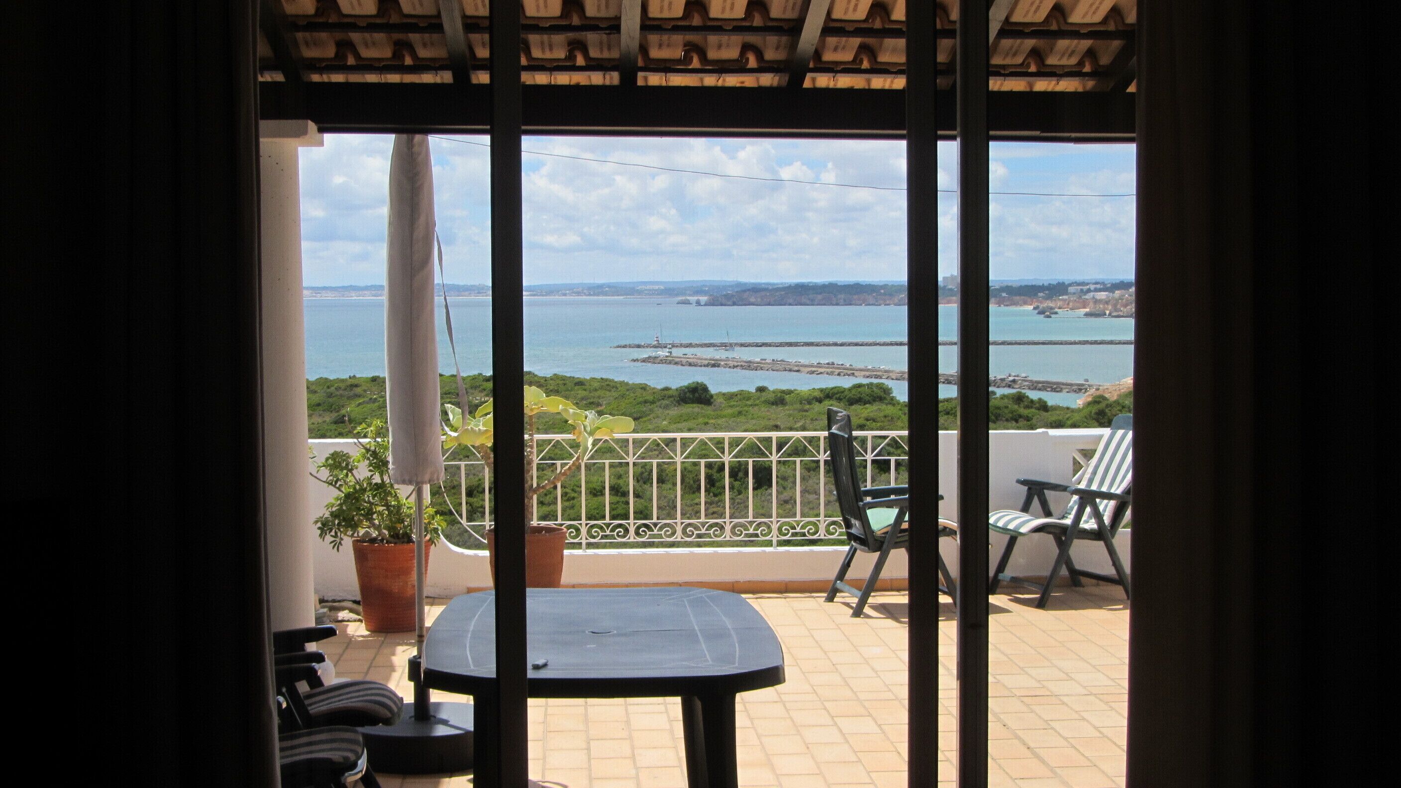 Ein Balkon mit Meerblick, einem Tisch, Stühlen und Topfpflanzen.