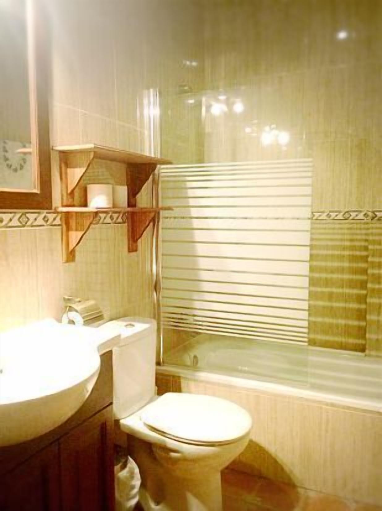 Un baño con inodoro, lavamanos y una ventana con persianas.