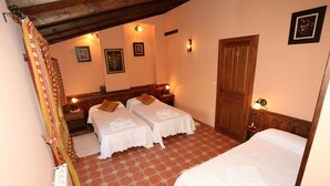 Ein Zimmer mit zwei Einzelbetten, einer Holztür und einem Fliesenboden.