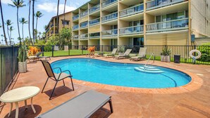A hotel with a swimming pool, lounge chairs, and palm trees. - Gorgeous Oceanfront Condo with Spectacular Views! (Kihei)