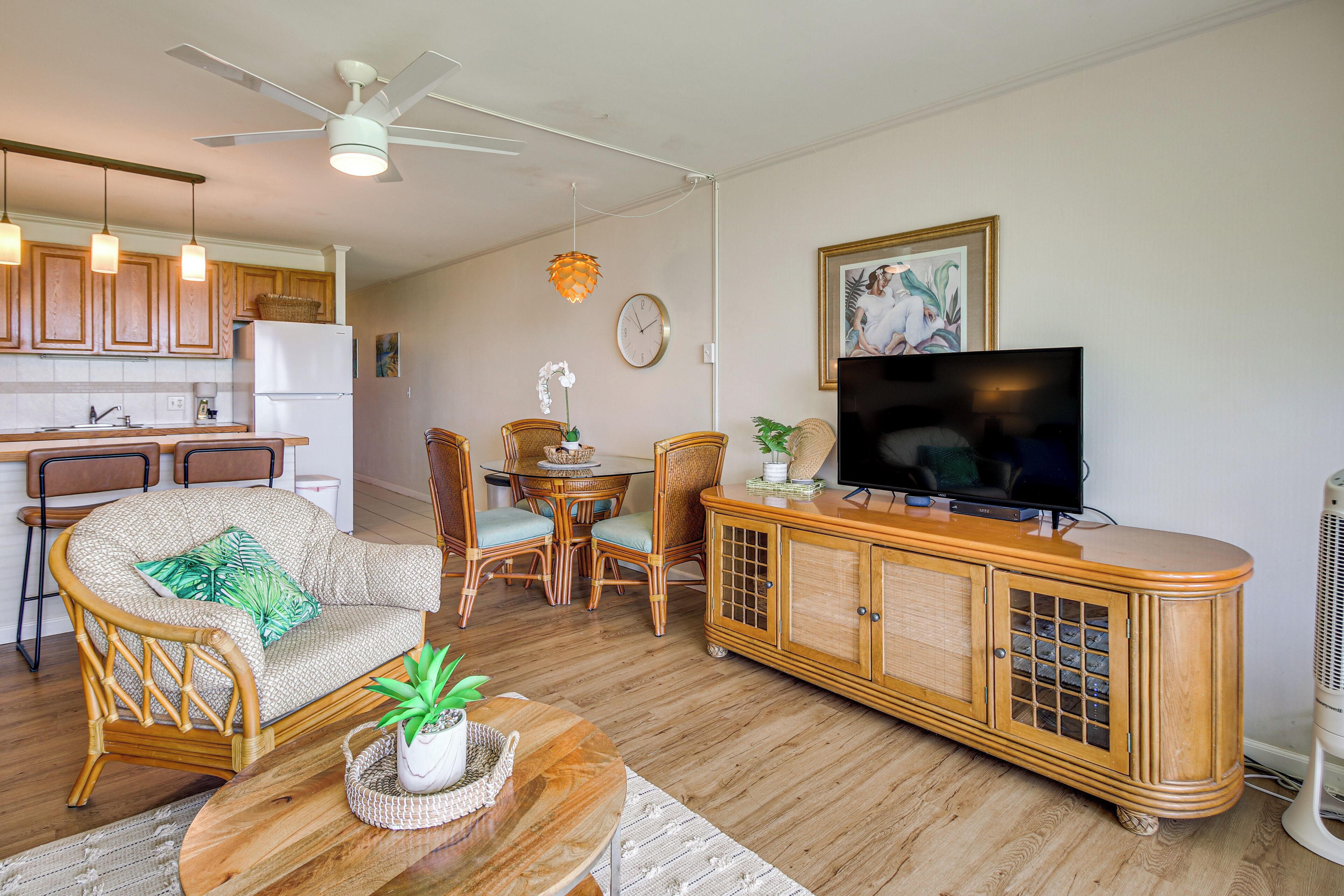 Una sala de estar con sofá, sillas, televisor y un mueble de madera.