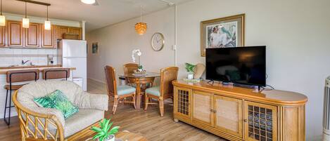 Una sala de estar con sofá, sillas, televisor y un mueble de madera.