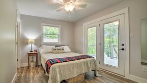 A bedroom with a bed, a ceiling fan, a nightstand with a lamp, and a window. - Lake Barkley Waterfront Home w/ Deck & Boat Dock! (Cadiz)