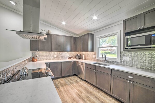 Una cocina moderna con armarios de madera oscura, una campana extractora de acero inoxidable y un amplio ventanal que proporciona luz natural.