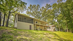 A two-story house with a large window on the first floor, a covered porch, and a staircase leading to the second floor. - Lake Barkley Waterfront Home w/ Deck & Boat Dock! (Cadiz)