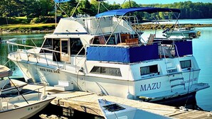 A white boat named MAZU docked at a pier with a blue canopy. - Maine Bed & Boat, MAZU on the scenic Damariscotta River (Damariscotta)