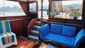 A cozy cabin with a blue sofa, a striped chair, and a wooden staircase. - Maine Bed & Boat, MAZU on the scenic Damariscotta River (Damariscotta)