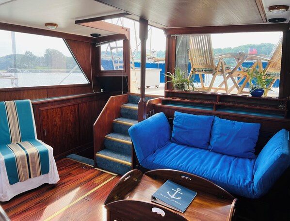 A cozy cabin with a blue sofa, a striped chair, and a wooden staircase.