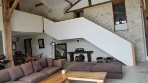 A spacious living area with a wooden staircase, a sofa set, and a fireplace. - Restored barn from late 18th century with pool (Champniers)