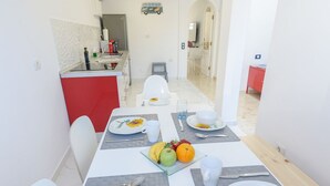 Comedor con mesa dispuesta para dos, con platos decorados con girasoles, un frutero y un vaso de agua.