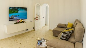 Una sala de estar con televisor de pantalla plana, un sofá, una mesa de centro y un mueble de pared.
