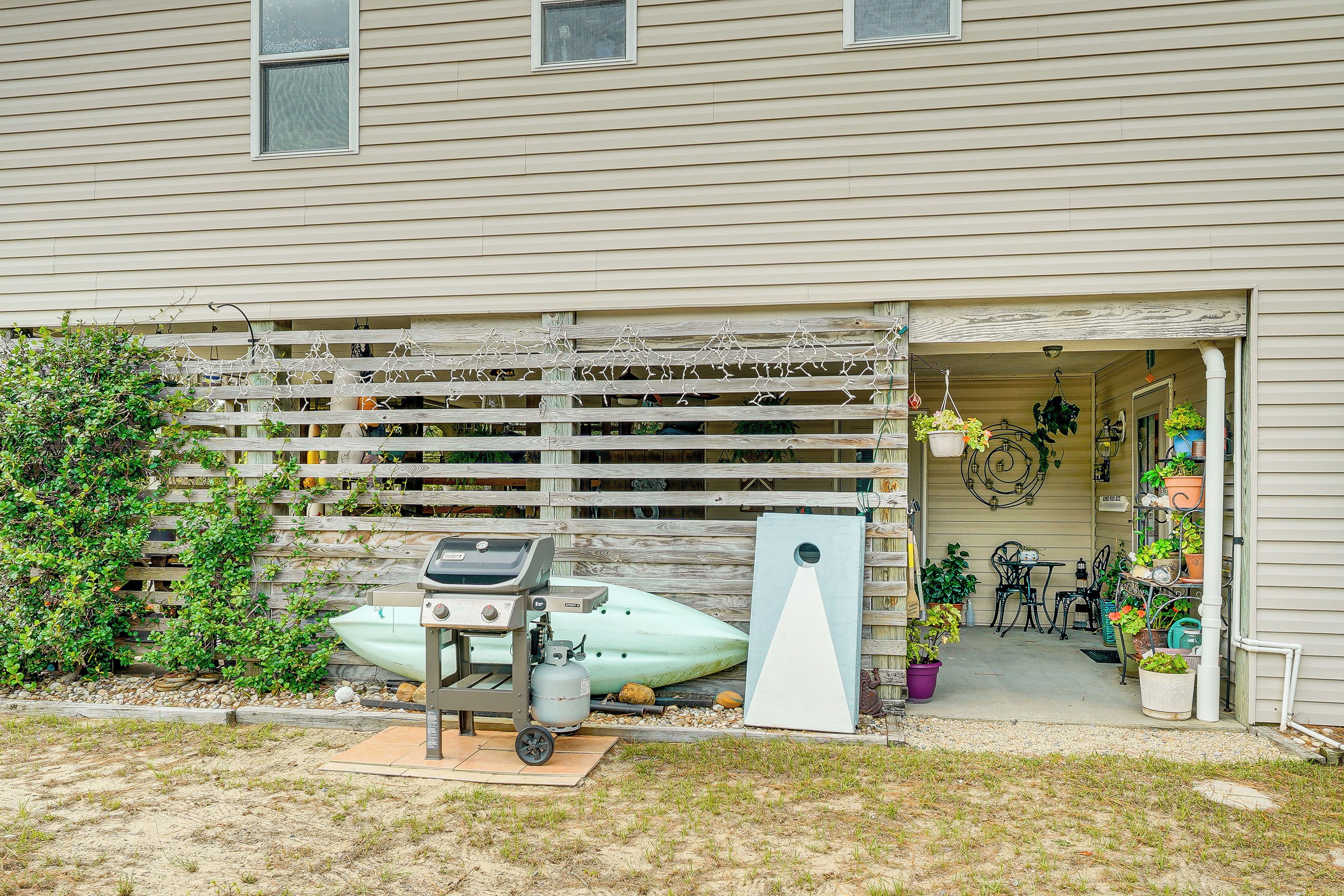 A house with a covered porch, a barbecue grill, a boat, and potted plants.