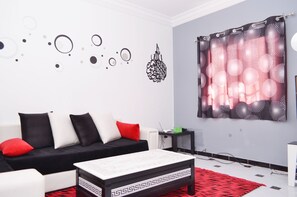 A modern living room with a black and white sofa, a red and white patterned curtain, and abstract wall art. - Chic T3 Akid Lotfi WIFI (Bir El Djir)