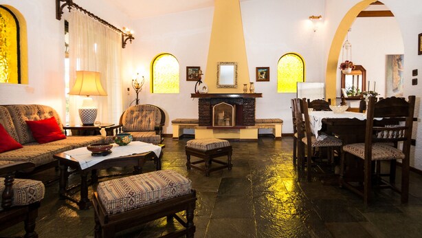 Una sala de estar acogedora con muebles estampados, una chimenea y un comedor con sillas y mesa de madera.