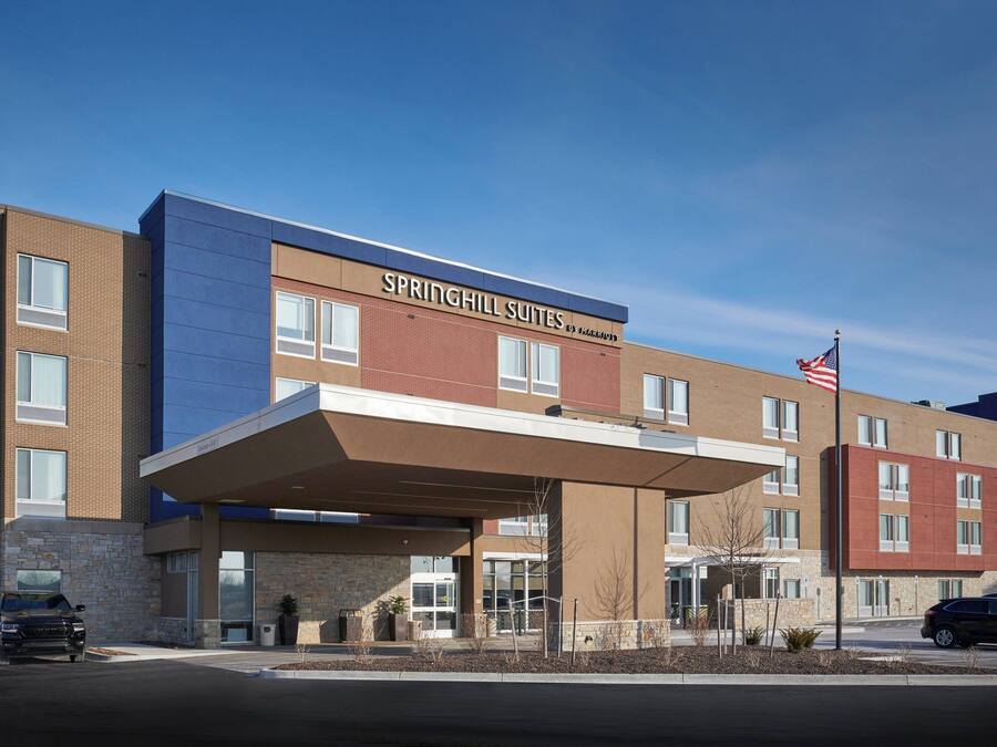 A modern hotel with a covered entrance, a stone facade, and an American flag.