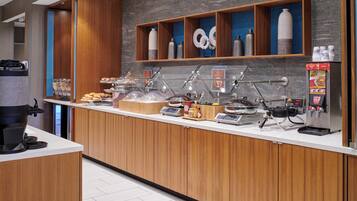 Un bar à petit-déjeuner moderne, équipé d’une machine à café, d’un coin pour préparer le thé et offrant une variété d’aliments.