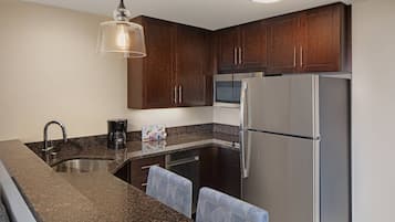 Una cocina moderna con armarios de madera oscura, electrodomésticos de acero inoxidable y encimera de granito.
