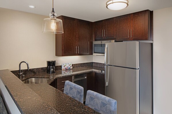 A modern kitchen with dark wooden cabinets, stainless steel appliances, and a granite countertop.