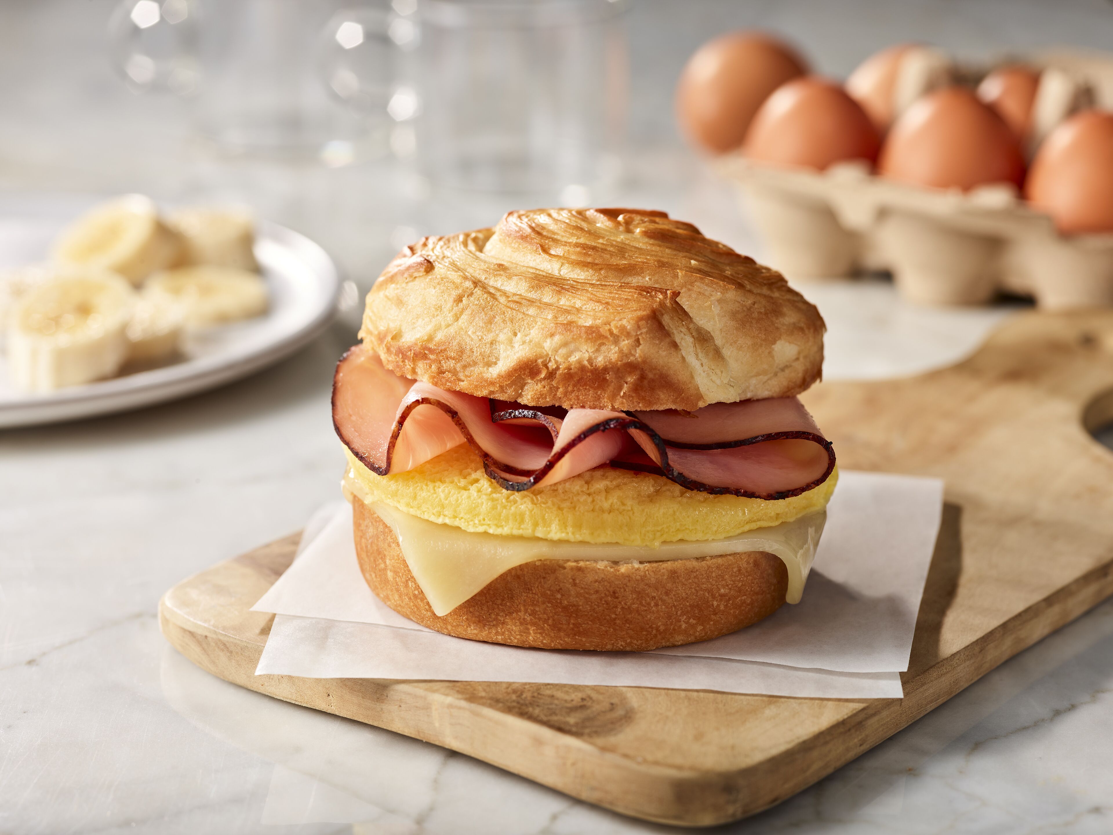 Ein belegtes Brötchen auf einer Holzplatte.