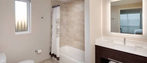 A modern bathroom with a bathtub, toilet, and vanity with a mirror.