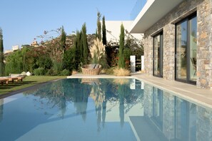 A modern pool with clear water, surrounded by a landscaped garden with various plants and a wicker basket. - Villa Ammos,  great view by the beach, next to the sea  (Ferma)