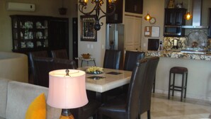 A dining area with a table, chairs, a lamp, and a kitchen in the background. - Downtown Penthouse-Style Apartment (Puerto Vallarta)