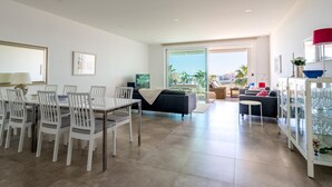 A modern living room with a dining area, a sofa, and a glass cabinet with glasses.