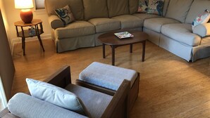 A living room with a sectional sofa, a small table, and a lamp.