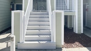 Eine Treppe mit weißen Geländern führt zu einem Balkon im zweiten Stock.