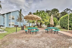 A courtyard with picnic tables, a trash bin, a bench, and a large umbrella. - Easy Walk to Pool, Family Kids Friendly by Disney (Kissimmee)