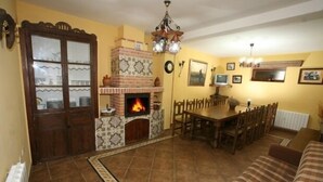 Una sala de estar acogedora con chimenea, muebles de madera y piso de baldosas.
