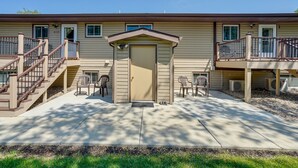 A two-story building with a front door, a small porch with chairs, and a staircase leading to an upper level. - Badlands Suite of Dakota Place Lodge in Medora! (Medora)