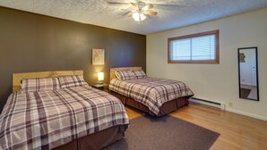 A bedroom with two beds, a ceiling fan, a window with blinds, and a mirror on the wall. - Badlands Suite of Dakota Place Lodge in Medora! (Medora)