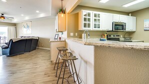 Una cocina moderna con armarios blancos, un microondas y una zona de bar con taburetes.