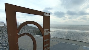 A metal structure with height markers and a pebble-stone pathway leading to a beach.