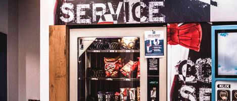A vending machine with a variety of snacks and drinks, a sign for 'COOL SERVICE,' and a K-LIX coffee machine.
