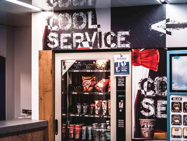 A vending machine with a variety of snacks and drinks, a sign for 'COOL SERVICE,' and a K-LIX coffee machine. - Ibis Budget Saint Brieuc Yffiniac (Yffiniac)