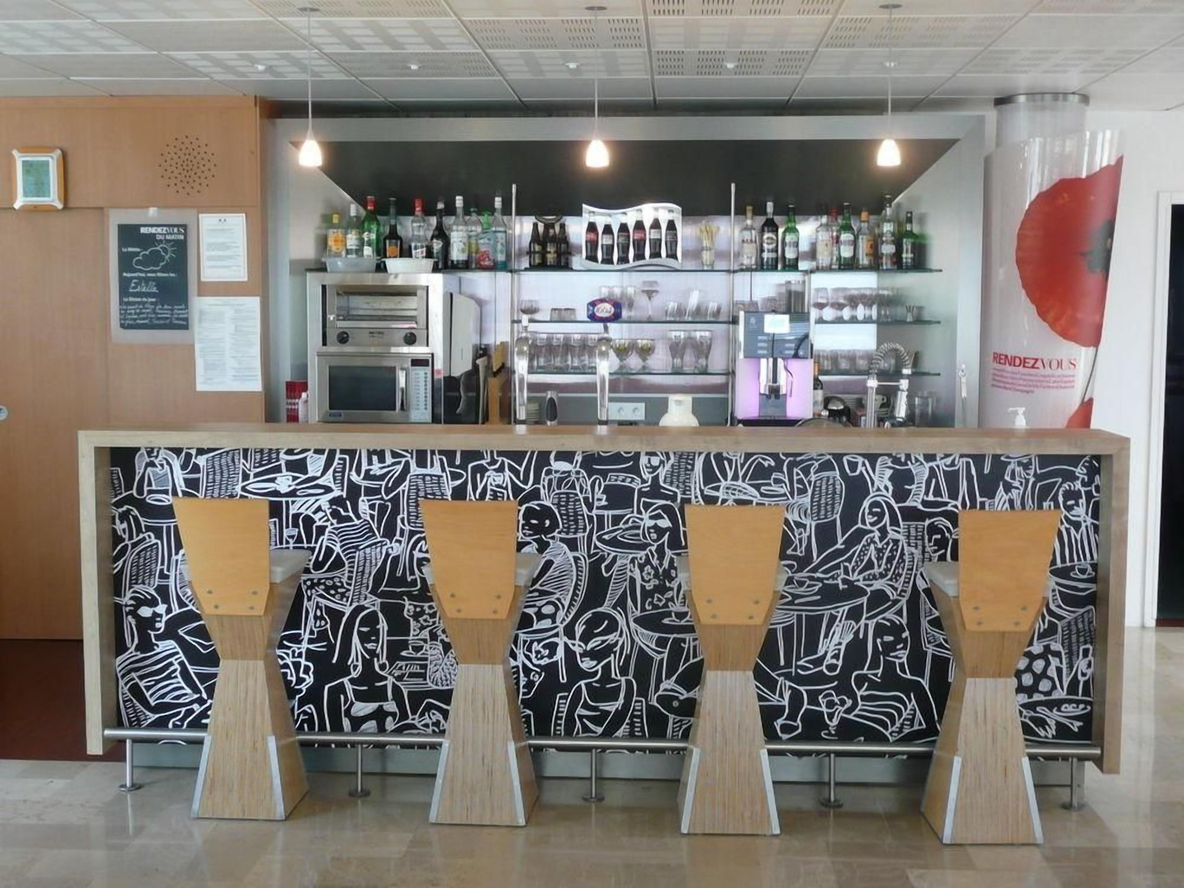 A bar area with a counter, various bottles, a microwave, and a menu board.