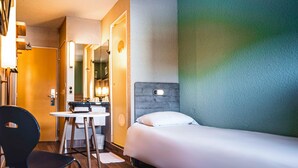 A hotel room with a bed, a desk, a chair, and a mirror. - Ibis Budget Saint Brieuc Yffiniac (Yffiniac)