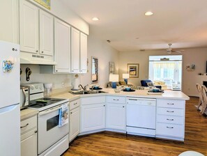 A modern kitchen with white cabinetry, a dishwasher, an oven, and a refrigerator.