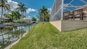 Un bâtiment moderne doté d’une façade en verre, d’une zone verdoyante et d’un plan d’eau.