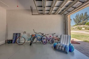 Un garage avec des vélos, un fauteuil gonflable bleu et une vue sur l’extérieur.