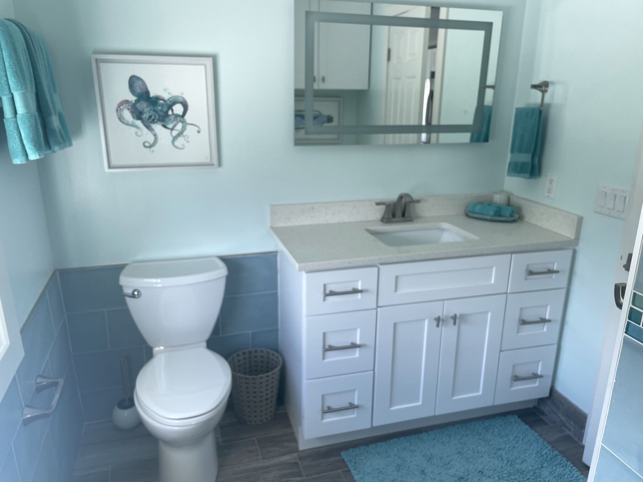 A bathroom with a toilet, sink, and cabinets.