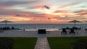 A beachside patio with outdoor seating and umbrellas, overlooking the ocean.