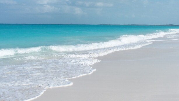 A beach with clear turquoise water and white sand.