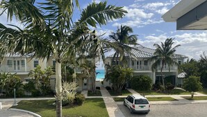 A residential area with two-story houses, a white van parked on the street, and a clear view of the ocean in the background.
